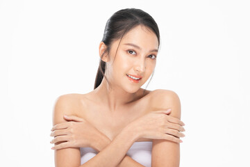 Asian Glowing skin woman with natural makeup smiling gently and crossing arms on bare shoulders,...