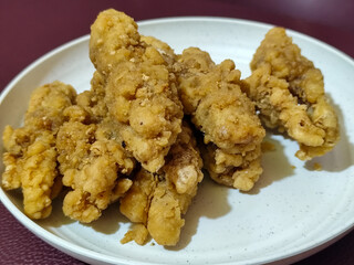 A plate of crispy golden fried chicken fillet, served on a blurred background.