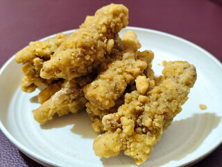 A plate of crispy golden fried chicken fillet, served on a blurred background.