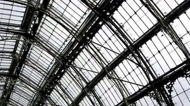 A close up of the intricate glass panels and iron supports of the Crystal Palace, showcasing its Victorian design