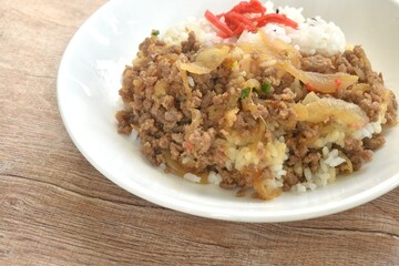fried ground beef with onion or soboro donburi on rice black sesame topping pickled red ginger on plate