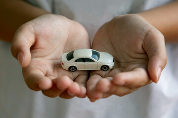 Toy car on hands; Car insurance and safety concept