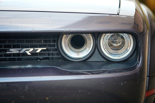 Minsk, Belarus. Jul 07, 2024. Dodge with emblem SRT on grille and headlight in midges closeup. Agressive style, american muscle car. Supercharged Dodge front light, body exterior. Selective focus