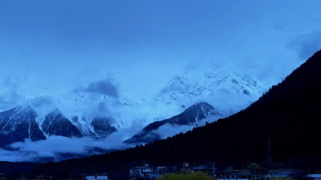 A snow - capped mountain surrounded by clouds and mist, time - lapse photography