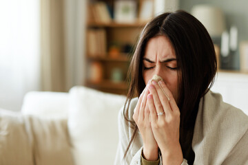 Young Woman Sick at Home Blowing Nose in Cozy Living Room with Warm Lighting