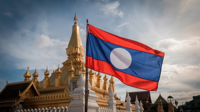 Flag laos waving proudly in front of ornate golden Buddhist temple with traditional Lao architecture