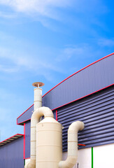 Wet scrubber exhaust air treatment system outside of production factory building against blue sky vertical background, low angle view with copy space