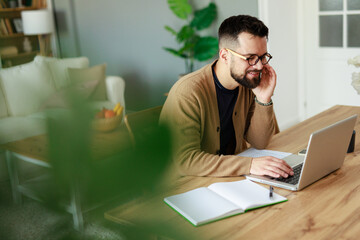Young Caucasian Man Working from Home on Laptop in Bright Living Room with Relaxed Atmosphere