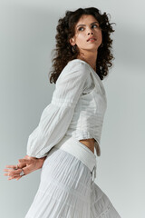 Stylish young woman poses gracefully in elegant white attire with flowing textures