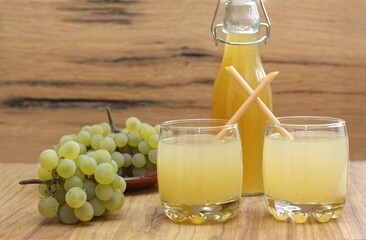 Two glasses of homemade delicious grape juice and fresh grapes. Made from fresh aromatic organic white grapes and honey or sugar.
