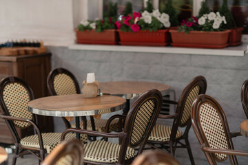 Tables Chairs Flowers: Outdoor cafe seating with wooden chairs, tables, and flowers for relaxed dining anytime.