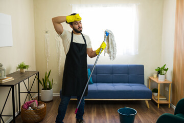 Tired housekeeper cleaning floor with mop taking break at home