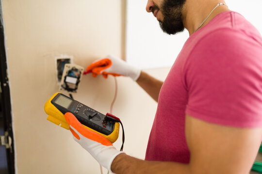 Closeup of electrician using digital multimeter checking voltage of electrical outlet