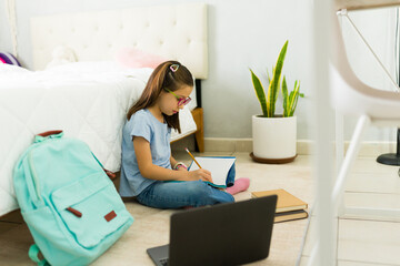 Young girl doing homework and taking notes in her bedroom