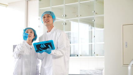 倉庫をチェックする衛生白衣を着た男女作業員 © metamorworks