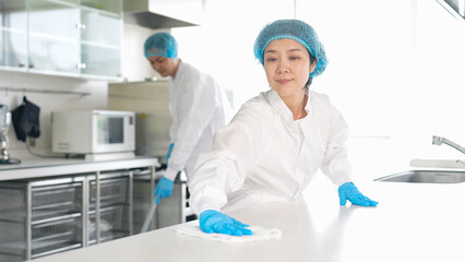 厨房を清掃する衛生白衣を着た男女スタッフ