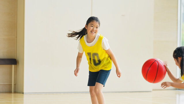 体育館でバスケットボールをする子供たち