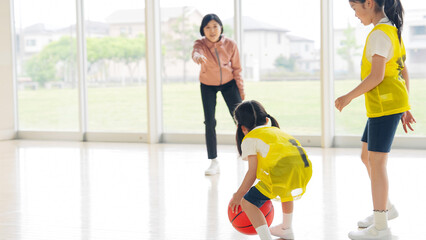 Obraz premium バスケットボールをする子供たちと指導する女性