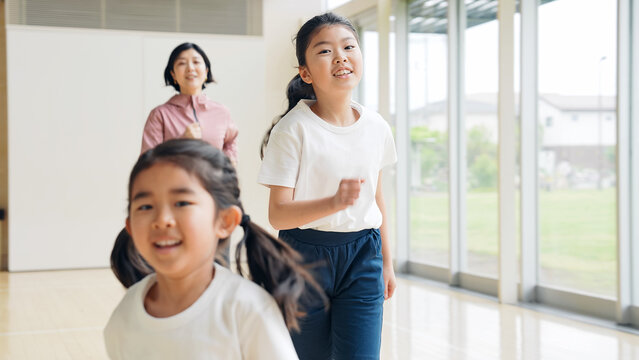 体育館の中を走る女の子と女性教師
