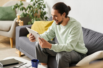 Young man enjoying leisure time at home while using a tablet in a cozy living space