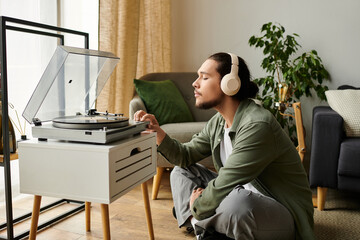 Young man enjoying music at home while relaxing by a turntable on a quiet afternoon