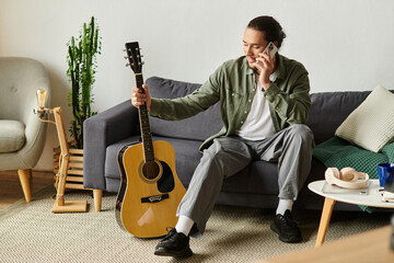 Relaxing at home, a young man plays guitar while talking on the phone