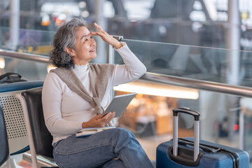 elegant senior woman using digital tablet during sitting in airport terminal while waiting for boarding,elderly people with modern lifestyle,airlines travel,journey on summer vacation trip