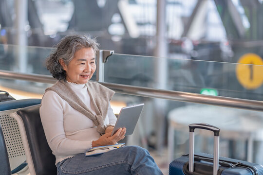 elegant senior woman using digital tablet during sitting in airport terminal while waiting for boarding,elderly people with modern lifestyle,airlines travel,journey on summer vacation trip