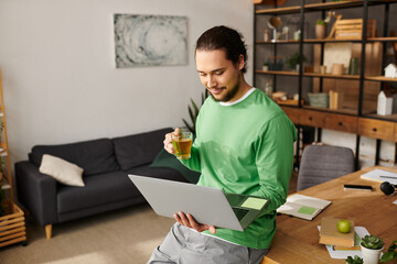 Young handsome man enjoying tea while working at home in a cozy and stylish environment