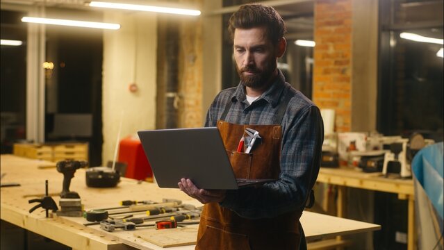 Caucasian wood master man typing laptop shopping app online in workshop builder handyman guy using Internet pc carpenter male buying goods artist architect browsing website small business cyberspace