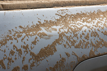 Muddy car door close-up. Part of car in the dust