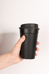 hand holding a cup,A woman's hand holds a black mug with coffee on a white background.Reusable plastic drink cup, thema coffee
