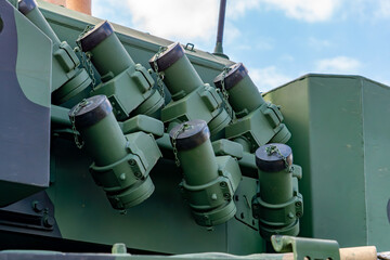 smoke grenade launchers mounted on an armored vehicle, green military equipment against the sky