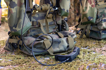 camo backpacks and military tactical equipment placed on camouflage netting during a display or...