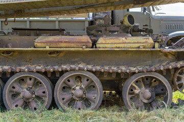 rusty tracks and road wheels of a Cold War-era tracked military vehicle standing on grass.