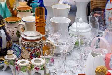 wine glasses, a decorative beer stein, and porcelain items displayed for sale at a flea market....