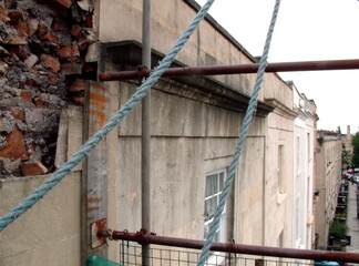 A building with scaffolding and a damaged wall.