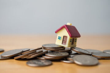 House on stack coins crash on wooden table with white background copy space. Risk and financial...