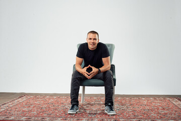 Confident Young Man Sitting on Chair in Studio Setting