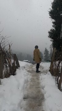 Backshot of Person Walking Alone in Snowfall Through Mountain Valley