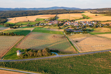 A bird's-eye view of grain fields in the Taunus Mountains in Hesse in summer, with a village in the...