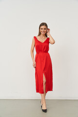 Female model showcases stylish red dress in fashion studio setting with elegant pose