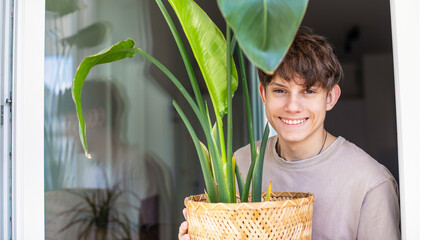  Cute cheerful teenager bought and brought home a green houseplant