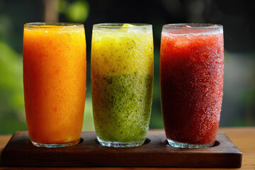 Three colorful fruit juices unfiltered looks refreshing and natural an appealing assortment displays on wooden tray for healthy lifestyle