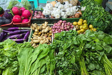 A vibrant assortment of fresh vegetables, leafy greens, and root spices displayed at a traditional...