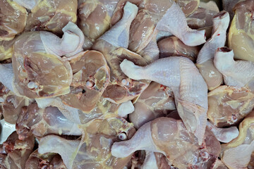 A pile of fresh raw chicken drumsticks and thighs arranged closely together at a local market.