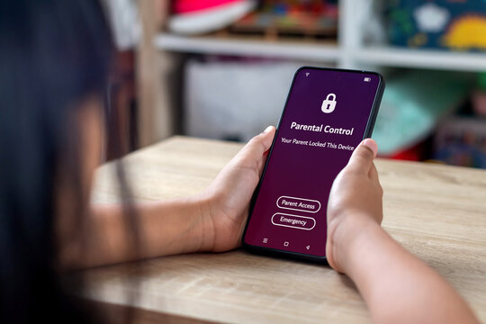 A young Asian girl holding a locked smartphone with parental control notification on the screen