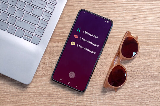 A smartphone on a desk with notification of missed call and new message on the phone screen