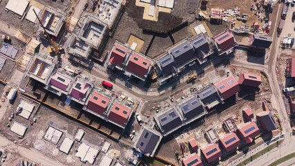 Aerial view of housing development construction site with eco friendly houses and construction machinery on green belt land