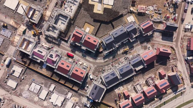 Aerial view of housing development construction site with eco friendly houses and construction machinery on green belt land